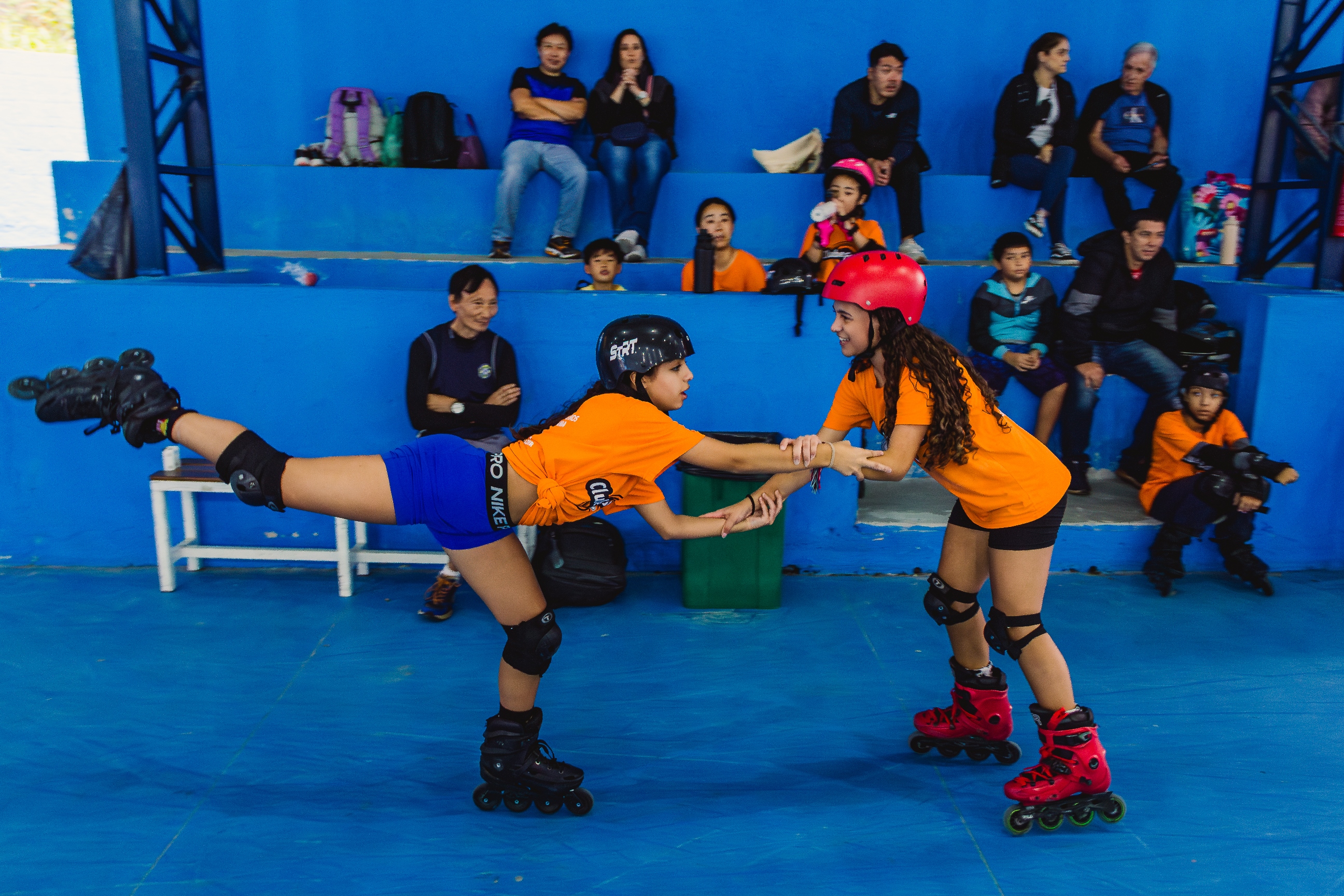 Crianças e adultos patinando juntos em um ginásio.